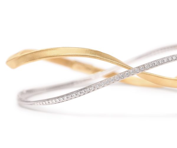 The Marco Bicego Marrakech Two-Strand Diamond Bangle is shown in a close-up shot on a white background, featuring two intertwined metallic bracelets: one gold with a ribbed texture and the other silver, encrusted with small diamonds.