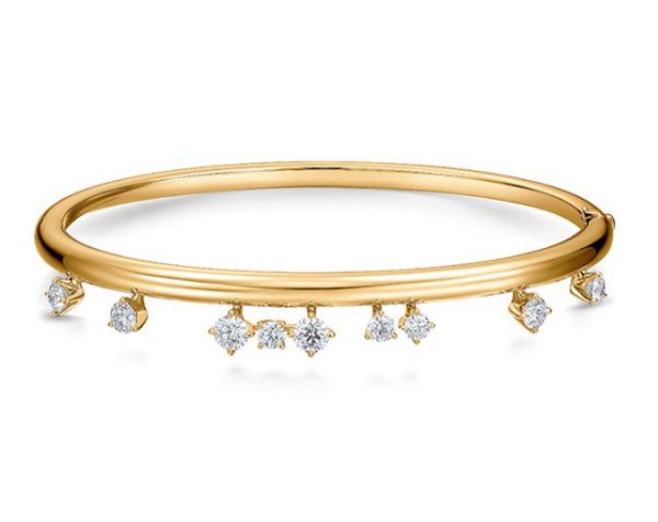 The Hearts on Fire Barre Floating Diamond Bangle is a sleek gold bracelet adorned with small, dangling diamond charms evenly spaced around it. The bracelet boasts a smooth and polished finish, exuding an elegant and sophisticated appearance. The sparkling diamonds add a touch of luxury to this exquisite piece.