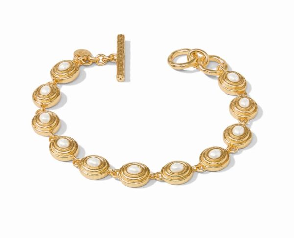 The Julie Vos Tudor Tennis Bracelet - Pearl features a design of linked gold circular elements, each adorned with a white pearl-like bead at its center. The bracelet closes with a toggle clasp and boasts an elegant, sophisticated design that exudes classic and timeless appeal.