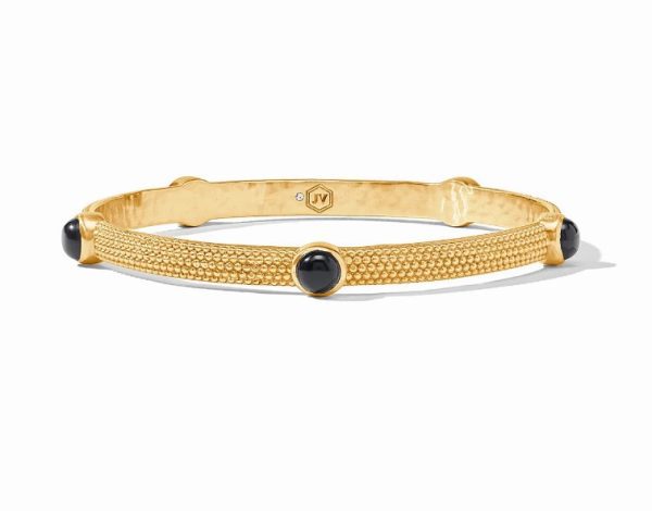 The Julie Vos Cabochon Bangle Bracelet in Obsidian Black features a textured gold design embellished with four equally spaced black onyx stones. A small hexagonal logo mark adorns the inner side of the bracelet, set against a plain white background.