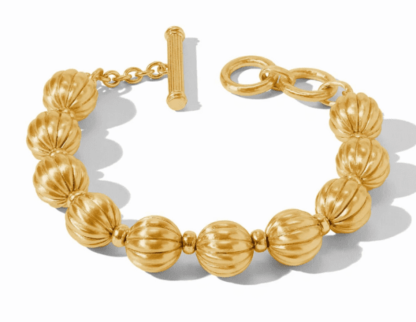 The Julie Vos Cirque Bracelet is a sleek gold accessory featuring round, fluted beads linked together by small, smooth round links. It has a stylish toggle clasp with a bar and ring design, and lies flat on a white surface, casting a subtle shadow.