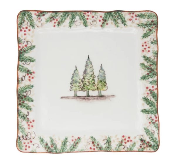 The Arte Italica Natale Square Dinner Plate showcases a central illustration of three Christmas trees. Its border is adorned with a festive pattern of holly leaves, red berries, and swirling vines, all highlighted by an elegant touch of gold trim.