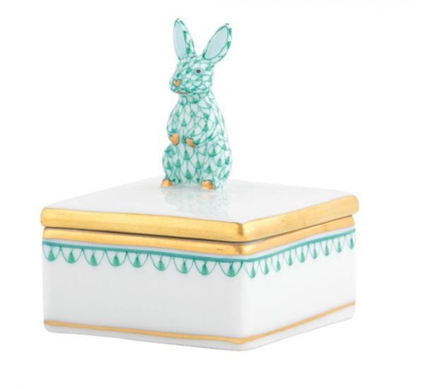 The Herend Bunny Box Figurine - Green is a small, square white porcelain box with gold edges and green leaf patterns. The lid features a sitting rabbit figurine adorned with matching green leaf patterns.