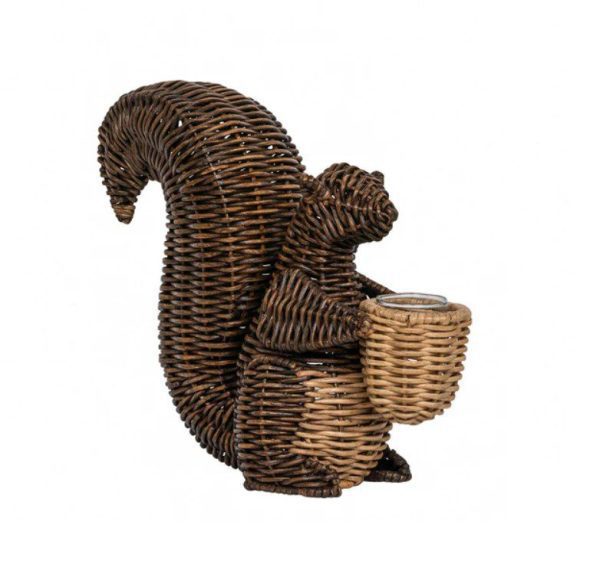 The Juliska Devon Willow Squirrel Flameless Candle Holder is a decorative wicker sculpture of a squirrel standing upright and holding a small wicker basket in its front paws. Crafted with intricate weaving, the squirrel's body and tail feature dark wicker, while the basket is made from lighter wicker. The background is plain white.