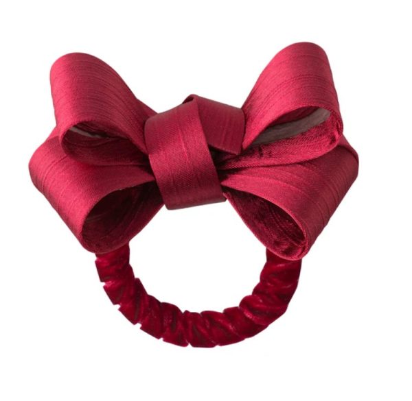 A Juliska Tuxedo Napkin Ring in Ruby, featuring a large, shiny satin bow. The bow is neatly tied, offering a sophisticated and elegant appearance. The napkin ring boasts a fabric-covered band that complements the rich ruby color of the bow.