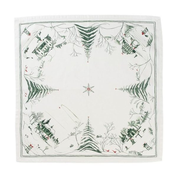 A square white Juliska Country Estate Winter Frolic Napkin - Evergreen, adorned with green illustrations of snowy village scenes at each corner. The images depict houses, trees, and people skiing or playing in the snow, creating a festive winter atmosphere. A central star-like snowflake is also present.