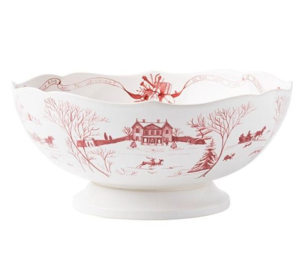 The Juliska Country Estate Winter Frolic 13" Centerpiece Bowl features a large, white ceramic design adorned with red illustrations of a winter scene, including a house, trees, and people in a sleigh. It boasts a decorative scalloped edge and sits elegantly on a pedestal base.