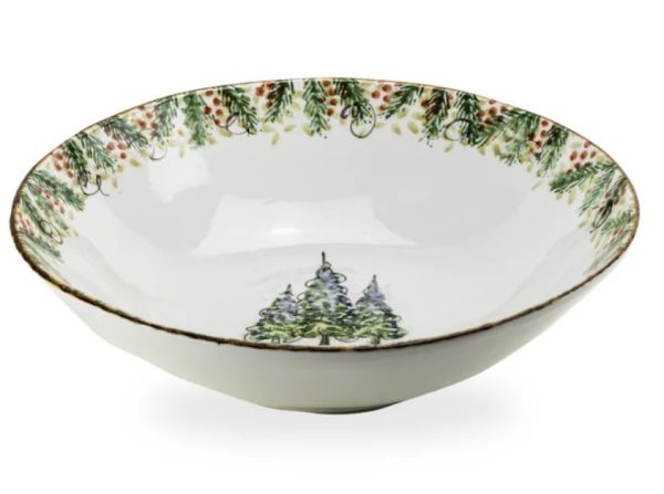 The Arte Italica Natale Medium Serving Bowl is a white ceramic piece featuring a festive design with green Christmas trees and red berries adorning the inner rim, along with a pair of Christmas trees depicted at the center of the bowl.