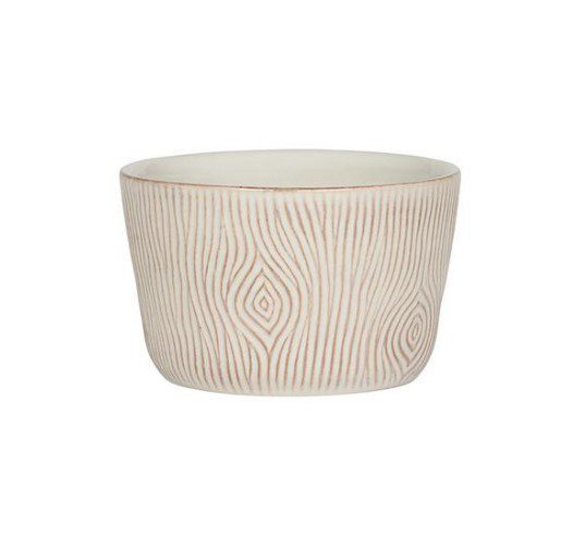 The Juliska Blenheim Oak Ramekin is a small white ceramic cup with a textured design that mimics wood grain. The intricate pattern includes both vertical lines and oval-shaped knots, giving the piece a natural and rustic aesthetic.