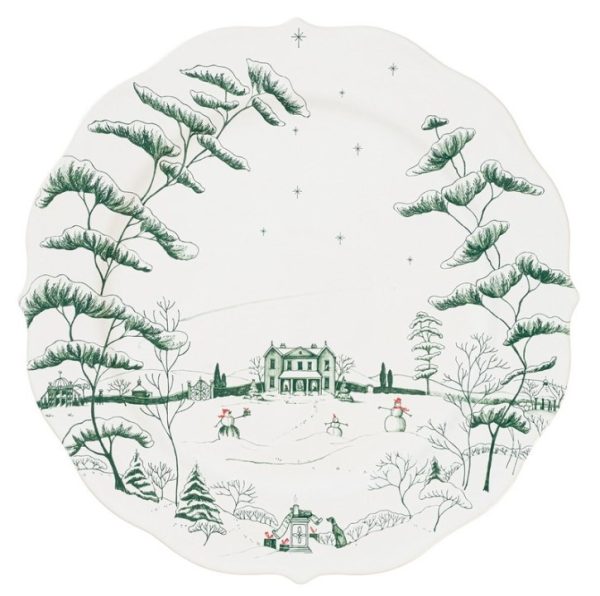 The Juliska Country Estate Winter Frolic Charger in Evergreen is a white ceramic plate featuring a winter scene with snow-covered trees and a charming house at the center. The landscape is adorned with snowmen, stars twinkling in the sky, and small houses along the bottom edge. The design showcases intricate detailing on the trees and buildings, primarily rendered in green.