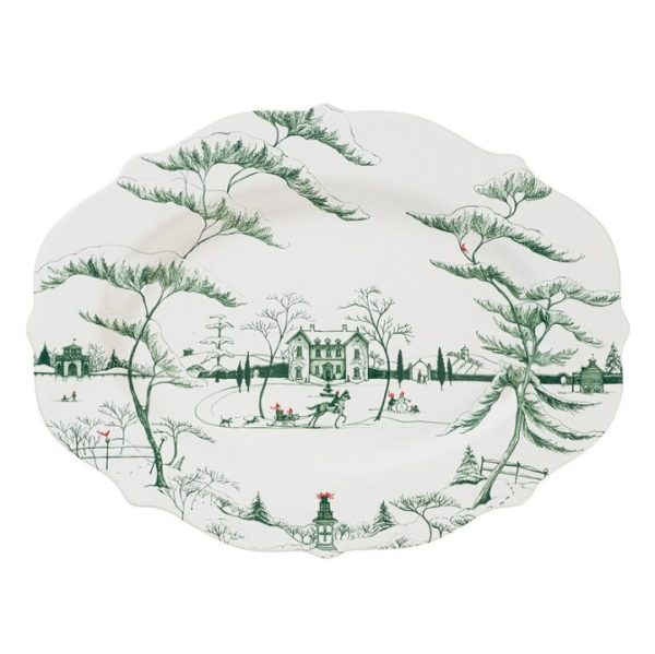 The Juliska Country Estate Winter Frolic 18" Platter - Evergreen showcases a beautifully illustrated winter scene, featuring serene trees, a large central house, and people joyfully ice skating and playing in the snow. The design also includes other quaint houses and an array of distant trees rendered in shades of green.