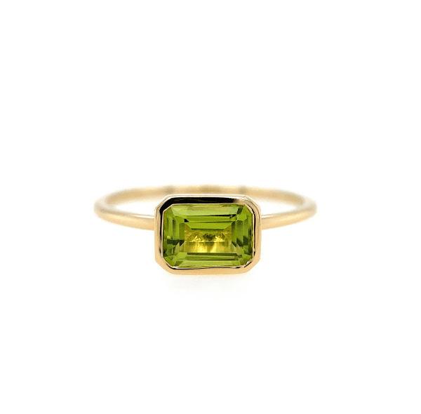 A delicate gold ring from Bromberg's Signature Collection featuring a rectangular-cut peridot, set in a minimalist gold band. The faceted gemstone displays a vibrant green color and is securely encased in a bezel setting.