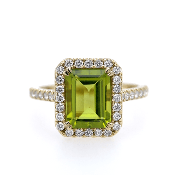 Introducing the Bromberg's Signature Collection Peridot and Diamond Ring: a stunning gold ring highlighted by a striking large rectangular peridot gemstone, framed by a halo of delicate round diamonds. The band is beautifully embellished with a line of small sparkling diamonds.