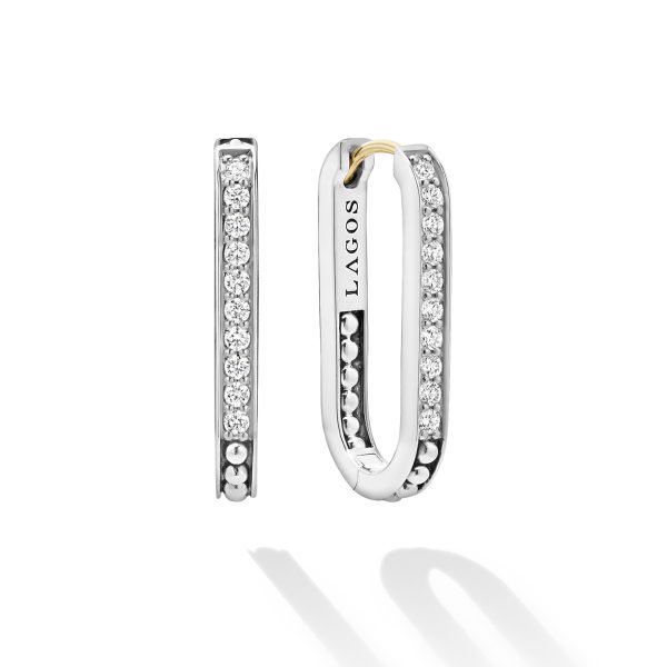 A pair of LAGOS Caviar Spark Linear Diamond Hoop Earrings in silver, featuring small sparkling diamonds. One earring is shown facing forward, showcasing the diamonds, while the other is angled to the side, revealing the "LAGOS" brand engraving.