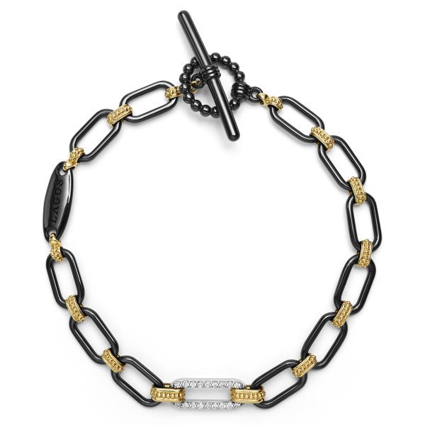 A stylish bracelet featuring black rectangular links with gold accents and a diamond-encrusted clasp. The LAGOS Signature Caviar 18K Gold and Black Ceramic Diamond Station Link Bracelet is fastened with a toggle clasp and has a metallic tag engraved with the word "LAGOS.