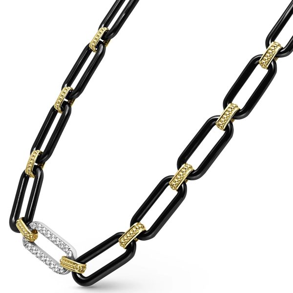 A close-up of the LAGOS Signature Caviar 18K Gold and Black Ceramic Diamond Station Link Necklace showcases its alternating black ceramic and gold links. One of the black ceramic links is adorned with small sparkling diamonds, enhancing the elegant touch of its contemporary design. The white background emphasizes the details of this stylish necklace.