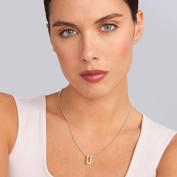 A person with short, dark hair and fair skin is wearing a light-colored top and the LAGOS Caviar Spark Small Linear Diamond Pendant Necklace. They have a neutral expression and are looking directly at the camera against a plain background.