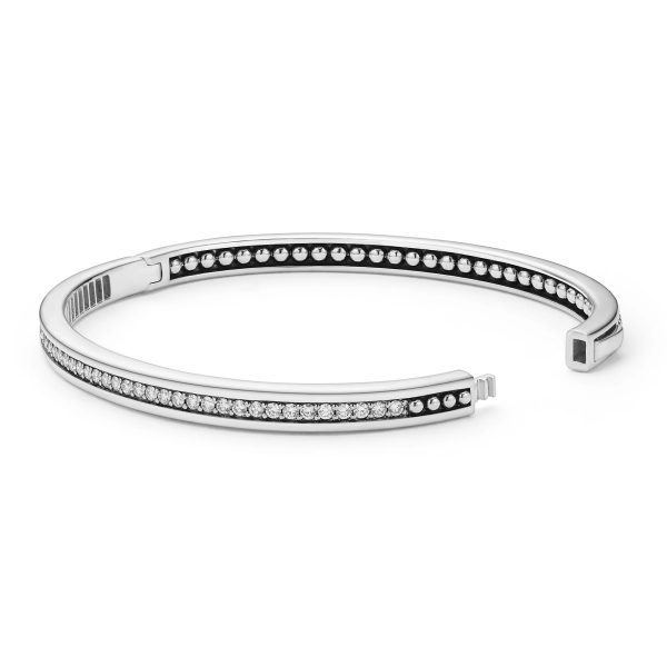 The LAGOS Caviar Spark Diamond Bangle Bracelet is a sleek, silver open bangle adorned with a row of small sparkling crystals on both the inner and outer edges, creating an elegant and sophisticated design.