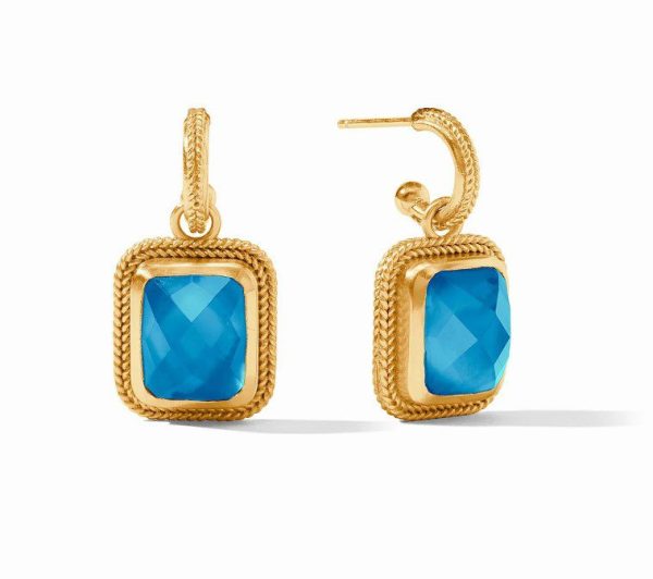 The Julie Vos Cheval Hoop & Charm Earrings in Iridescent London Blue feature two gold earrings with square-shaped blue gemstones. Each earring is adorned with a textured gold frame around the gemstone and comes with a gold hook for easy insertion into pierced ears. The faceted surface of the gemstones adds a touch of sparkle to these elegant pieces.