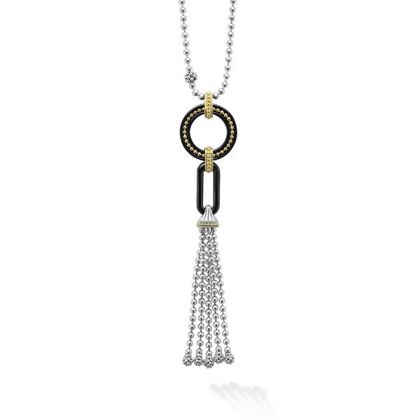 The LAGOS Black Caviar Two-Tone Black Ceramic Tassel Pendant Necklace showcases a circular pendant embellished with black and gold accents. Attached to the pendant is a black rectangular link that supports a tassel made of multiple silver chains. The chain is elegantly designed with small, silver beads.