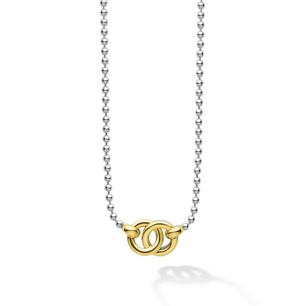 The LAGOS Signature Caviar Two-Tone Interlocking Pendant Necklace showcases a silver chain of small, round links and a prominent gold double-ring pendant at the center, with the rings interlocked. The shadow of the necklace is visible against the white background.