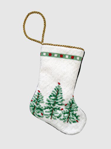 The "Baubles Stockings + Vietri Lastra Holiday Stocking" features a festive design, complete with a gold rope handle. It is adorned with green pine trees and red dots near the top border, all set against a crisp white background.