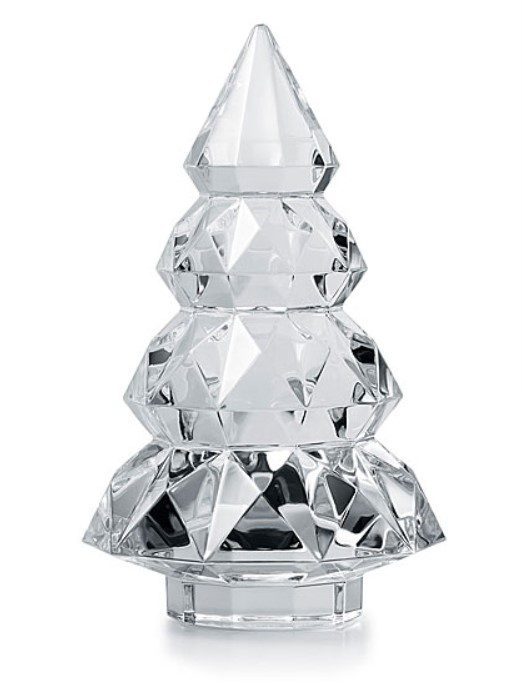 The Baccarat 2024 Louxor 7" Tree - Clear is a crystal sculpture shaped like a stylized Christmas tree, featuring geometric facets that reflect light. It boasts a sleek and modern appearance with a clear, reflective surface.