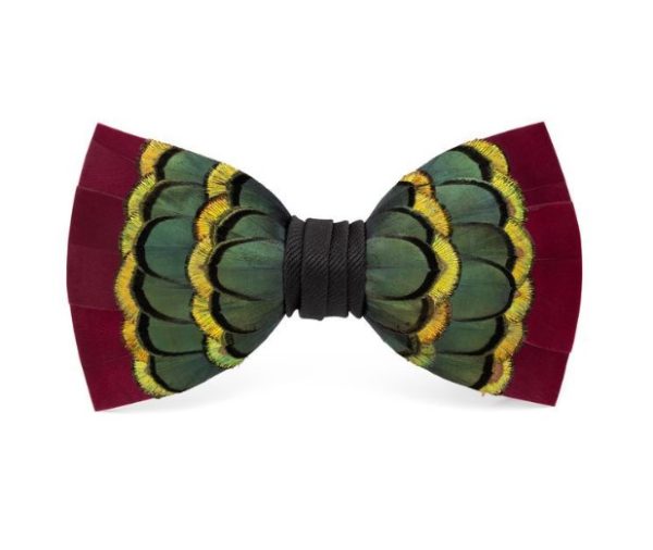 The Brackish Bow Tie - Willwood is a decorative bow tie made from feathers, featuring a design with layered green, yellow, and burgundy feathers arranged in a symmetrical pattern. The center is wrapped with black material, creating a striking contrast with the colorful feathers.