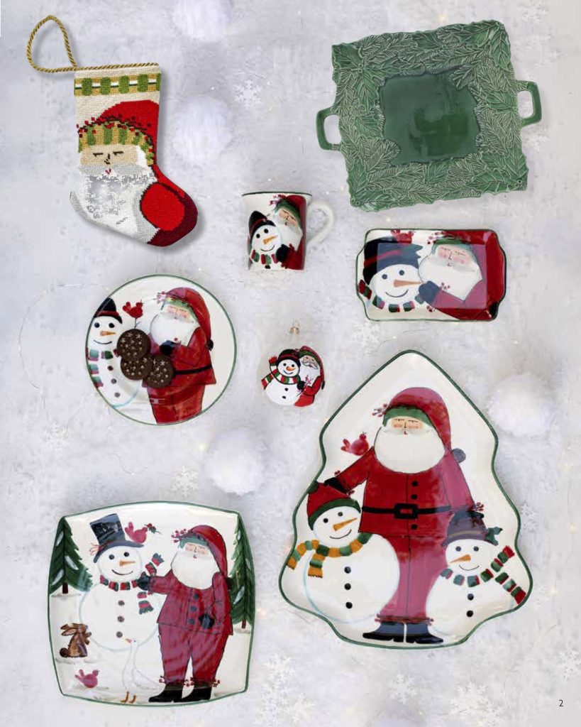 Festive holiday tableware and decor on a snowy surface. Includes plates and mugs with illustrations of snowmen and Santa Claus, a green decorative plate, and a small Santa-themed stocking.