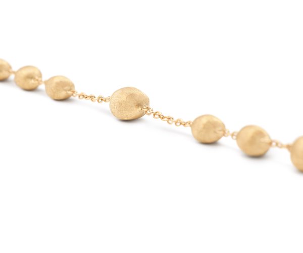 The Marco Bicego Africa Yellow Gold Station Bead Bracelet is a delicate creation, featuring round, textured gold beads evenly spaced along the chain. Set against a soft white background, it beautifully highlights the bracelet's elegant simplicity.