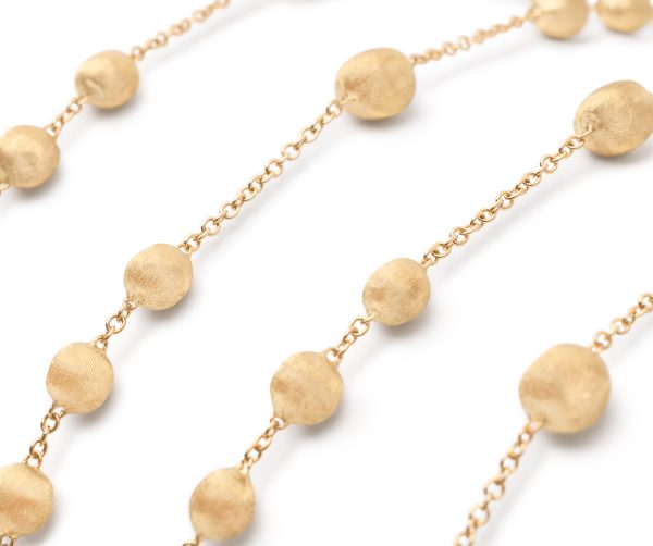 Close-up of the Marco Bicego Africa Yellow Gold Station Bead Long Necklace featuring oval and round textured beads evenly spaced along delicate links, set against a white background.