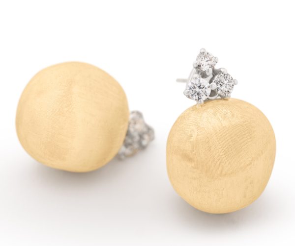 The Marco Bicego Africa Yellow Gold Stud Earrings feature a stunning textured finish, with each earring showcasing three small, round diamond accents at the top. Set against a white background, these earrings' elegant design is highlighted beautifully.