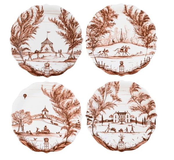 The Juliska Country Estate Harvest Party Plate set includes four vintage-style ceramic plates featuring brown illustrations that showcase pastoral scenes: a circus tent, horseback riding, a hot air balloon near a church, and a grand estate with people strolling, each framed by trees in a picturesque setting.