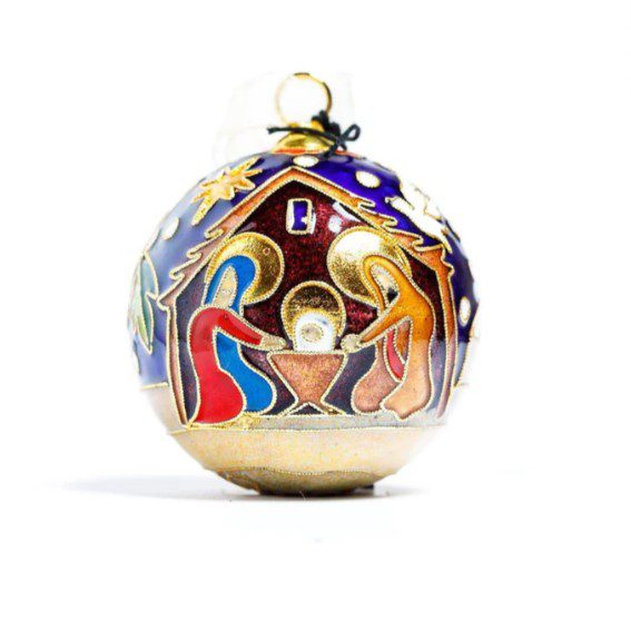 The Kitty Keller Round Cloisonné Christmas Ornament - Nativity showcases a nativity scene with Mary, Joseph, and baby Jesus in a stable under a shining star. This ornament is adorned with vibrant colors such as red, blue, and gold.