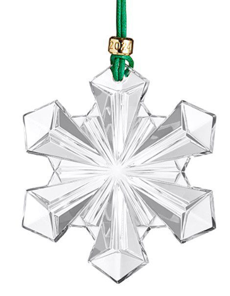 The Waterford 2024 Snow Crystal Ornament is crafted from clear, faceted glass in the shape of a snowflake with six pointed ends and intricate geometric patterns that beautifully reflect light. It hangs from a green ribbon adorned with a gold tag engraved "2024.