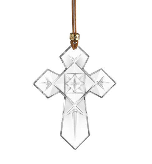 The Waterford 2024 Cross Ornament features a star pattern at its center, suspended from a brown leather cord adorned with a small gold bead.