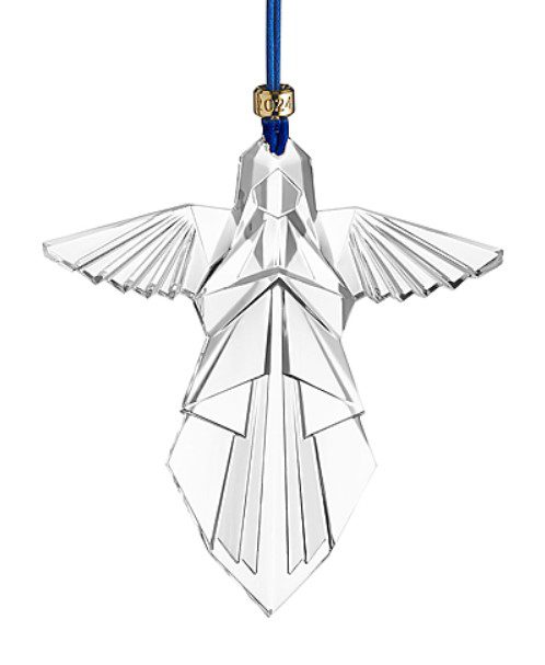 A crystal ornament known as the Waterford 2024 Angel Ornament is designed in the form of a stylized bird with outstretched wings and is suspended by a blue ribbon. The ornament's geometric facets contribute to its modern and elegant appearance, while a small gold tag near the ribbon reads "2024.