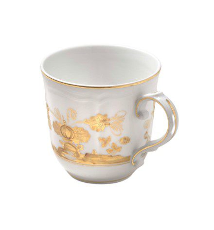 The Ginori 1735 Oriente Italiano Mug - Aurum is a white porcelain cup featuring intricate gold floral patterns and a gold rim, with an elegantly designed handle that complements its ornate style.