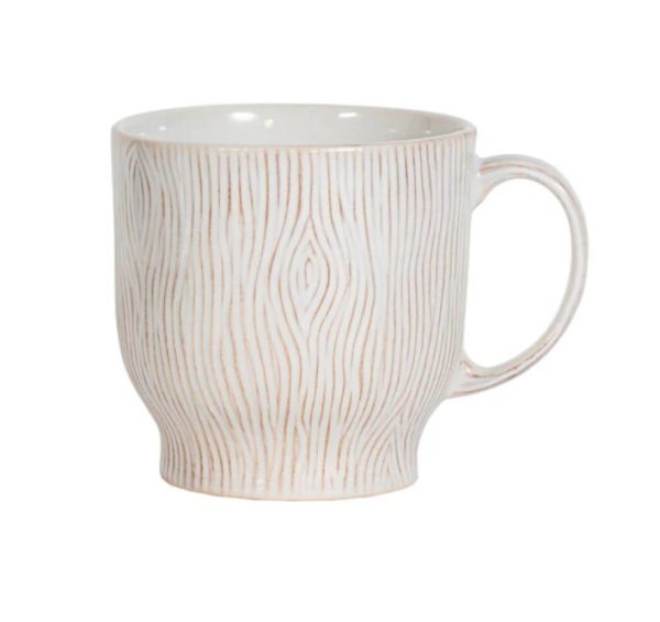 The Juliska Blenheim Oak Mug in Whitewash features a textured pattern reminiscent of tree bark, complemented by a smooth, curved shape and a single handle. Its design showcases a white base color enhanced by light brown lines.