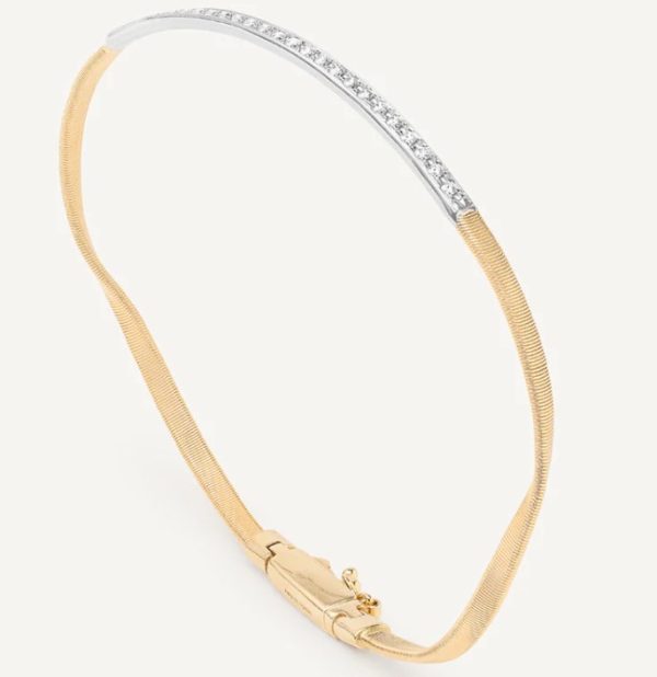 The Marco Bicego Marrakech Diamond Bar Bangle showcases a sleek, polished gold bracelet design accented with a silver segment adorned with small, sparkling diamonds. It features a hinge clasp for fastening and is set against a plain, light background.