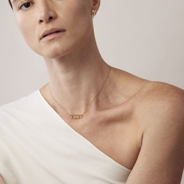 A person wearing a sleeveless white top is showcasing the delicate Hearts on Fire Barre Floating Diamond Pendant Necklace. The background is a soft, neutral tone.