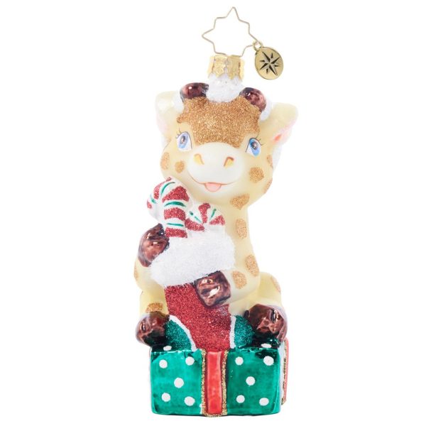 Introducing the Christopher Radko 2024 Children's of Alabama Ornament: a delightful festive decoration showcasing an adorable giraffe with a sparkling face, perched atop a green polka dot gift box. The giraffe is holding a red and white candy cane inside a vibrant red stocking, topped with a dainty gold star charm for an extra touch of holiday magic.