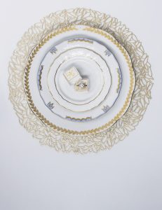 An engagement ring in a box under a place setting with stacked Herend dinnerware, the perfect addition to a wedding registry.