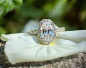 Oval halo yellow gold engagement ring with a large diamond surrounded by smaller ones, featured in Bromberg’s Diamond Sale.
