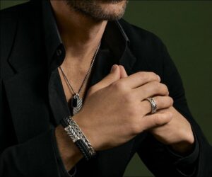 A man wearing David Yurman’s men’s jewelry collection, including a Chevron Tag necklace, cuff bracelet, and ring.