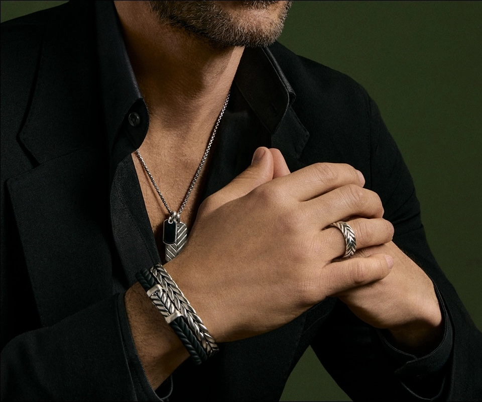 A man wearing David Yurman’s men’s jewelry collection, including a Chevron Tag necklace, cuff bracelet, and ring.